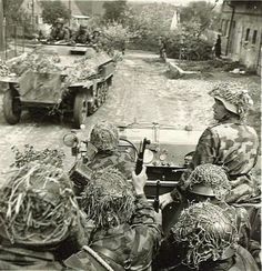 some soldiers are sitting in an army vehicle and one is pointing at something on the ground