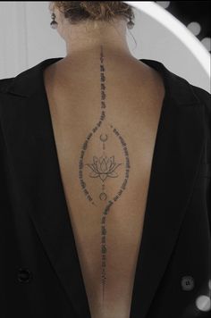 the back of a woman's neck with an intricate tattoo design on her lower back