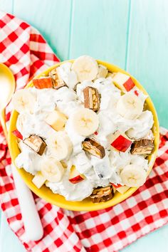 a bowl filled with fruit and nuts on top of a red checkered cloth next to a spoon