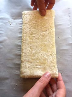 a person holding a piece of bread in their hand on top of a metal surface