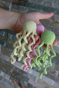 three crocheted sea creatures are held in the palm of someone's hand