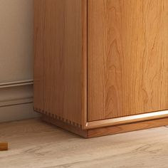 a wooden cabinet sitting on the floor next to a white wall and wood flooring