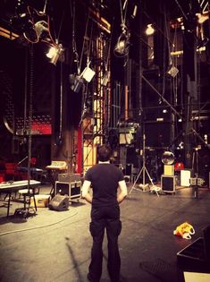 a man standing in front of a stage with lots of lights hanging from the ceiling