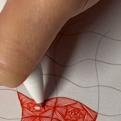 someone is drawing something with red ink on paper