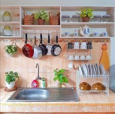 a kitchen with pots and pans hanging on the wall above the sink is filled with dishes