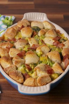 a casserole dish with broccoli and bacon in it on a wooden table