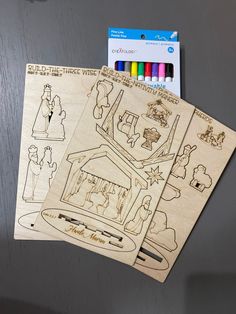 two wooden cut outs depicting the nativity scene with colored crayons and markers