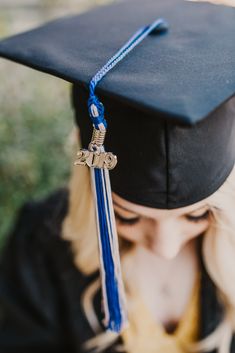 a woman wearing a graduation cap and gown with a blue tassel around her neck