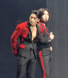 two men dressed in black and red standing next to each other