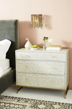 a white dresser sitting next to a bed in a bedroom