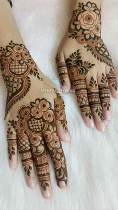 two hands with henna tattoos on them, one is showing the intricate design and the other has flowers