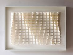 an art piece made out of white paper with wavy lines in the middle on a wall