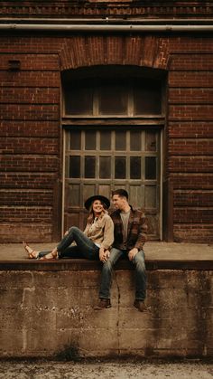 a man and woman sitting on the ledge of a building