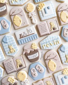 baby shower cookies are arranged in rows on a white tablecloth with blue and yellow accents