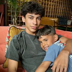 two young men sitting on top of a couch next to each other