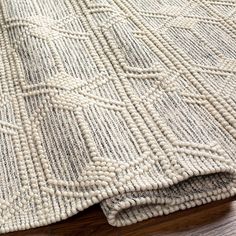 a close up view of a rug on the floor with wood floors and white fabric