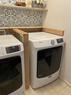 two white washers sitting next to each other on top of a tiled floor in front of a wall