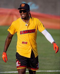 a man in yellow shirt and black shorts standing on soccer field with his arms out