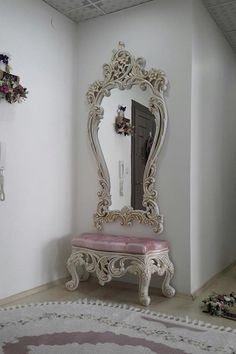 an ornately decorated mirror sits in the corner of a room next to a pink bench