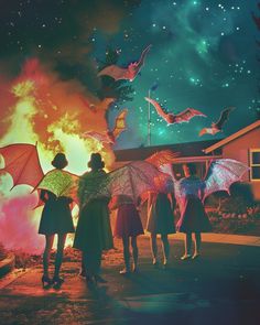 four people standing in front of a fire with umbrellas and bats on their heads