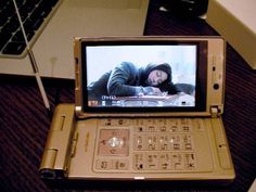 an open laptop computer sitting on top of a wooden desk next to a cell phone