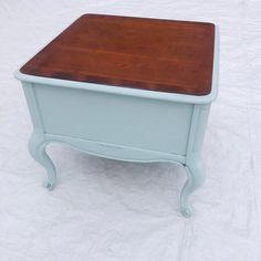 a small wooden table sitting on top of a white sheet