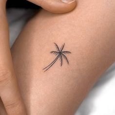 a small palm tree tattoo on the back of a woman's thigh and leg