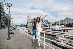 two women standing on a bridge with their arms in the air