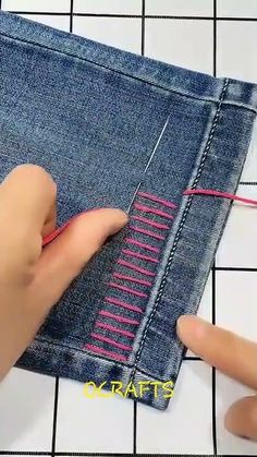 someone is sewing on the side of a pair of blue jeans with pink stitchs