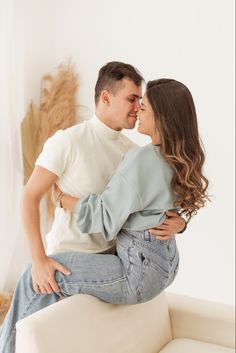 a man and woman sitting on top of a white couch