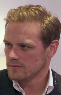 a close up of a person wearing a suit and tie looking at the camera with a serious look on his face