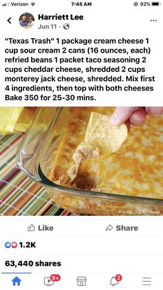 someone is holding a cracker over a casserole in a glass dish on the table