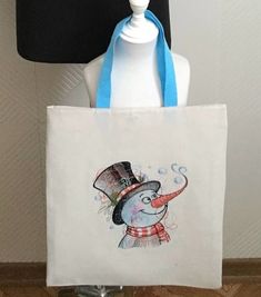 a white tote bag with a snowman wearing a top hat and scarf on it