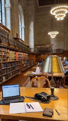 a laptop computer sitting on top of a wooden table in a library filled with books