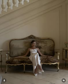 a woman sitting on top of a couch under a chandelier in a room