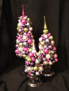 two christmas trees made out of ornaments on a black background