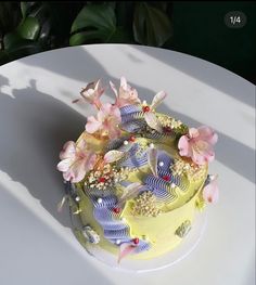 there is a yellow cake with flowers on the top and bottom layer, sitting on a white table