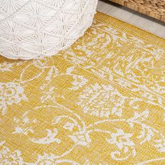 a yellow and white rug on the floor next to a wicker basket