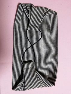 a black and white striped shirt laying on top of a pink surface