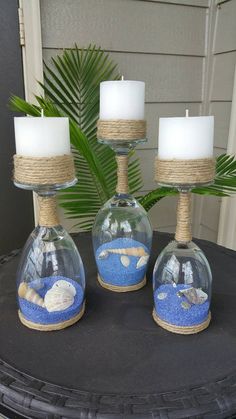 three glass vases with sand and shells in them on top of a black table