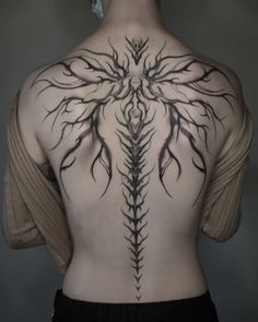 the back of a man's body with an intricate tattoo design on his chest