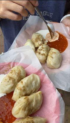 some food is on a pink plate and someone is holding a fork in the other hand