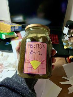 a person holding a jar of pickles in front of a computer