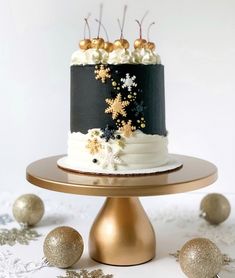 a black and white cake with gold snowflakes on it sitting on top of a table