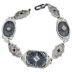 This is a radiant Diamond and Garnet Frosted Rock Quartz Crystal 14 Karat White Gold Bracelet. The classic antique Art Deco bracelet of great beauty is set with rectangular and oval carved Rock Crystal plaques (also known as camphor glass). The three plaques are each pierced with a single diamond sparkler which is elegantly framed in white gold. Between the rock crystal sections are white gold filigree sections each centered by a wonderful round faceted red Garnet. The bracelet has elegant filig Silver Rectangular Diamond Bracelet With 17 Jewels, Victorian Polished Bracelets For Formal Occasions, Antique Polished Bracelets For Formal Occasions, Ornate Diamond Jewelry For Collectors, Ornate Diamond Jewelry Collectible, Antique Gemstone Bracelet For Anniversary, Antique Intaglio Jewelry For Formal Occasions, Ornate Collectible Diamond Jewelry, Luxury Engraved Oval Bracelets