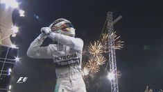 a man standing in front of a crowd wearing a white race suit and holding his fist up