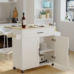 a white kitchen island with wine bottles and glasses on it