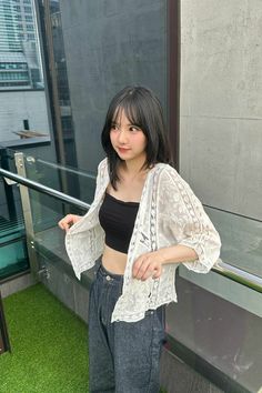 a young woman standing on top of a balcony next to a building with grass in front of her