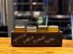 three different types of beer are in a wooden tray on a table with the words detroit, new york, blonde trip written on it