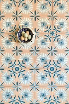 some eggs are in a bowl on a tiled floor with blue and white designs around it